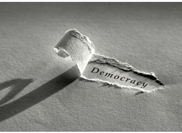 A ripped piece of paper revealing the word 'democracy'