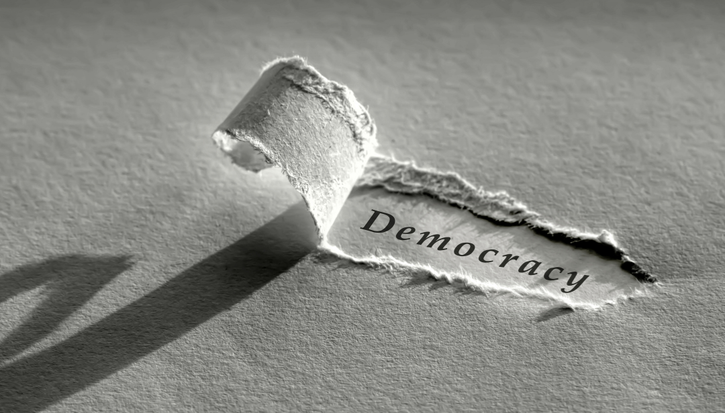 A ripped piece of paper revealing the word 'democracy'
