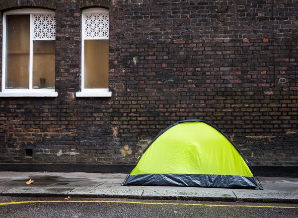 Small tent on the pavement of the city street in London, UK, with a homeless person sleeping inside