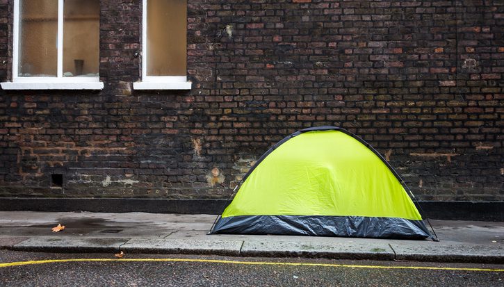 Small tent on the pavement of the city street in London, UK, with a homeless person sleeping inside