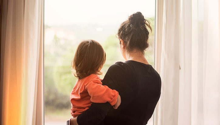 A mother and child from behind looking out of a window