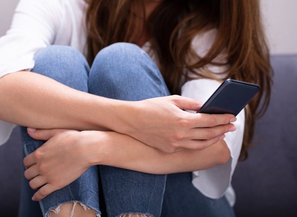 Close-up Of Woman Sitting On Sofa Texting Message On Smartphone