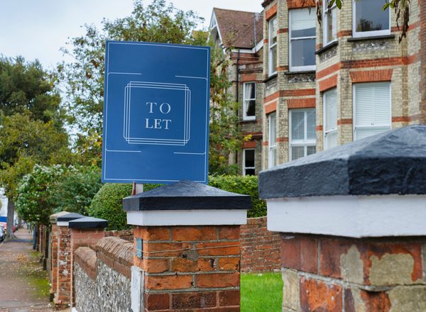 A 'To Let' sign outside a row of houses on a residential street, UK