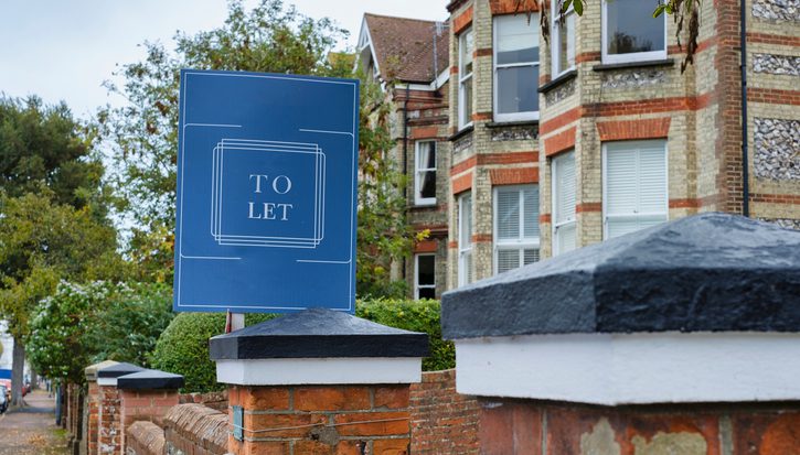 A 'To Let' sign outside a row of houses on a residential street, UK