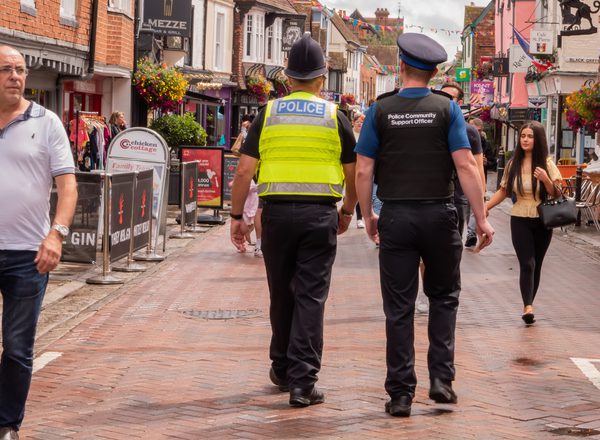 A photo of police officer and a community support officer walking down a quiet street in Kent