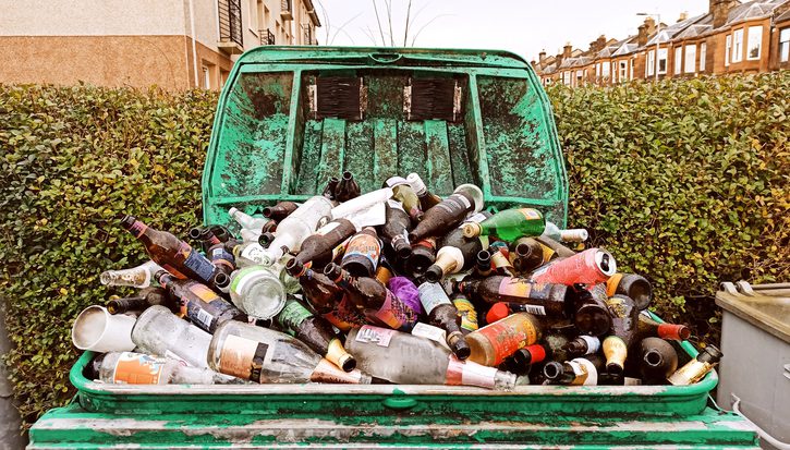 A huge overflowing recycling bin full of discarded empty bottles of alcoholic drinks
