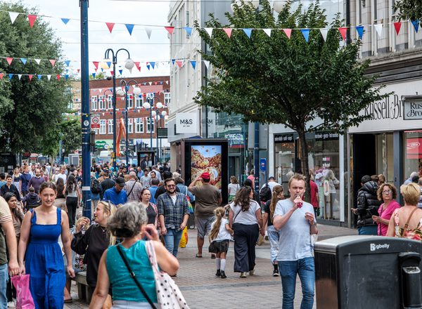 A busy high street in Kingston-upon-Thames, London. Shoppers walking beneath multi-coloured bunting