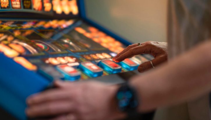An unrecognisable woman playing a slot machine in a social club