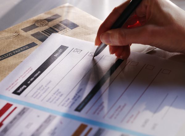 A woman’s hand filling in a postal ballot / voting form.