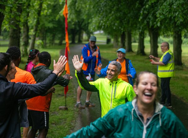 A diverse group of runners smiling and high-fiving spectators as they cross the finish line
