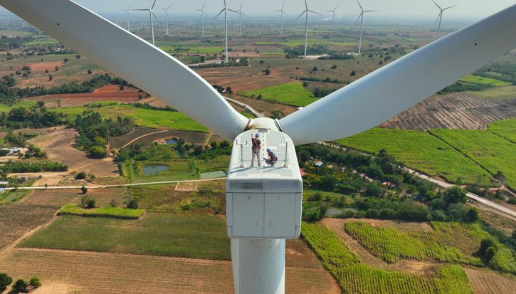A view from above a wind turbine with two engineers standing on top of it