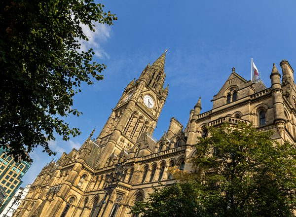 A photograph from below of the grand Manchester town hall building on a sunny day against a blue sky