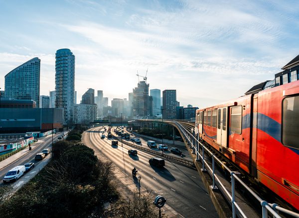 Train and cars on a motorway with London skyline in background
