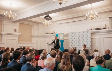 Audience facing Ed Davey, who is stood at a lectern.
