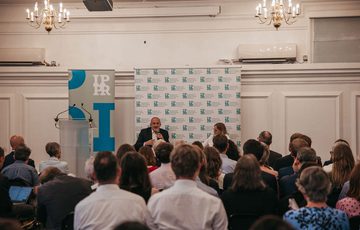 Audience facing Ed Davey who is sat and speaking into a microphone.