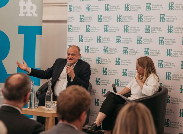 Ed Davey and Sarah Mulley sat in front of IPPR banners. Ed Davey is speaking into a microphone.