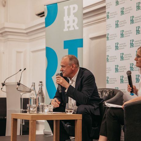 Ed Davey and Sarah Mulley are sat in front of IPPR banners. Both are holding microphones.