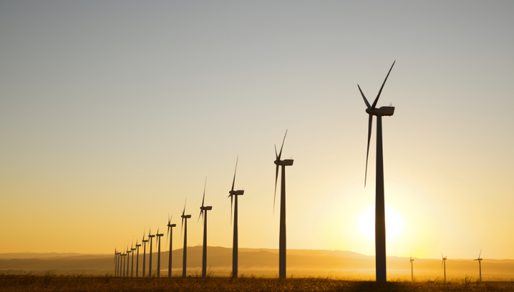 A line of wind turbines at sunset