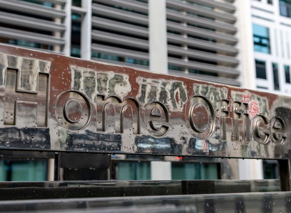 A closeup of an aged, graffiti-covered sign that reads Home Office